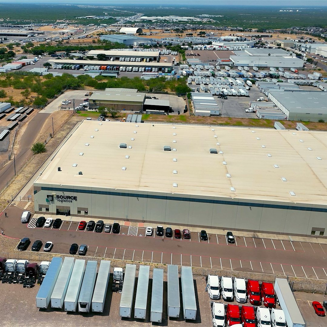 Aerial view of the large Source Logistics warehouse and distribution center with numerous parked trucks and trailers.